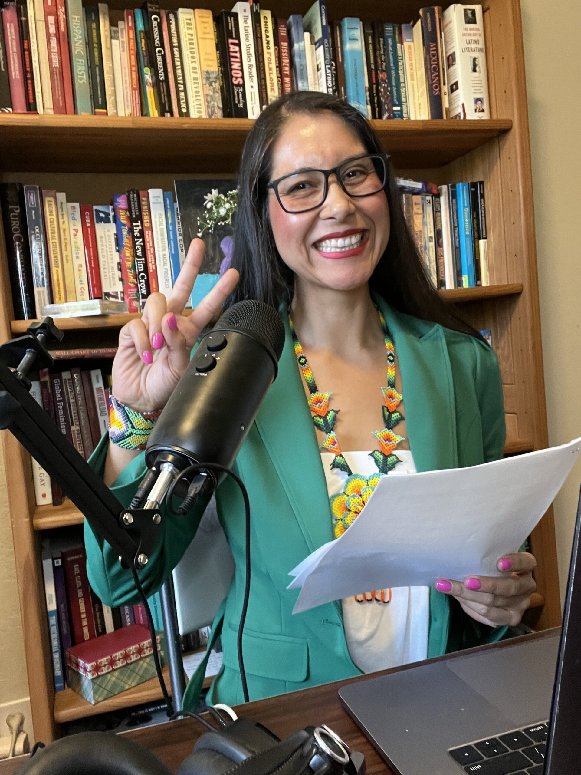 Dr. Hortencia smiling behind a podcast microphone